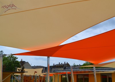 Beschattung der gesamten Terrassen - und Spielflächen mit insgesamt 11 Segeln aus Soltis 96 in unterschiedlichen Orange - und Gelbtönen.